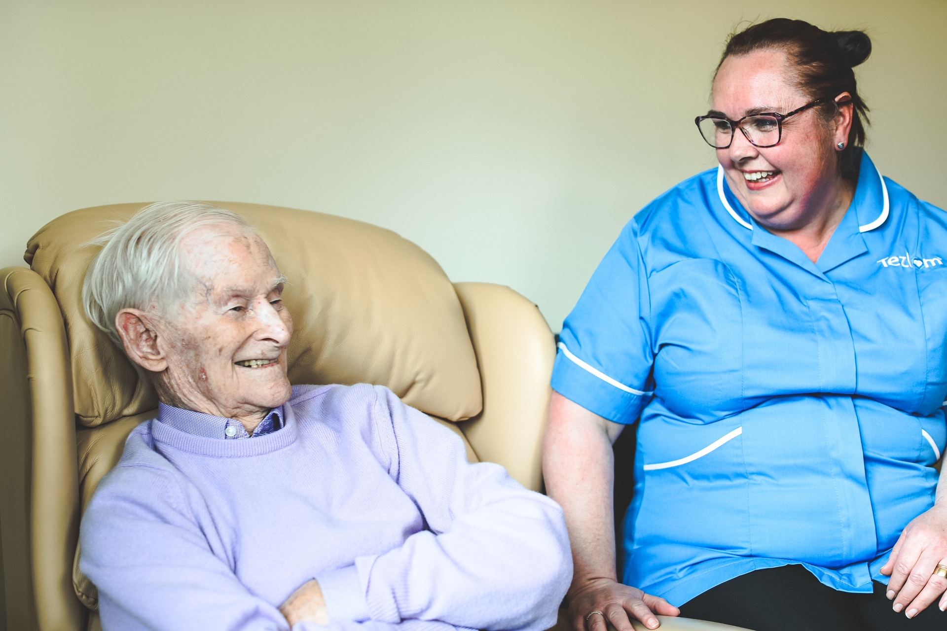 A Tezlom care assistant sharing a laugh with an elderly gentleman